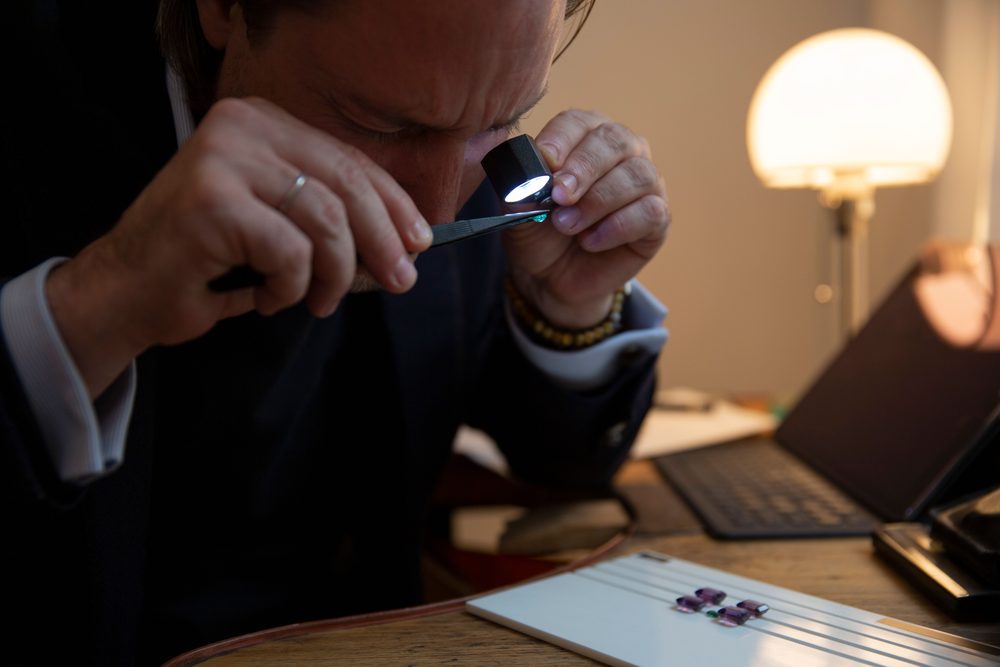 Maximilian Hemmerle prüft Edelsteine mit Juwelierslupe